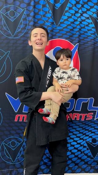 A dad in a black uniform holds his toddler