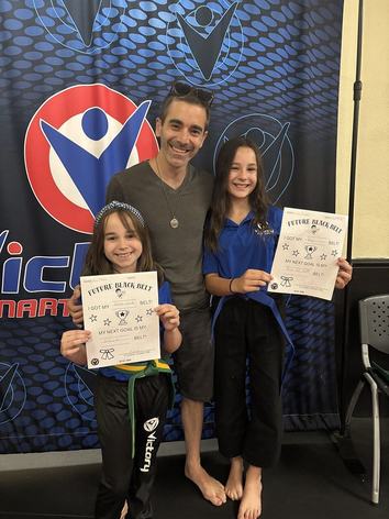 The same family today, the girls holding their belt certificates