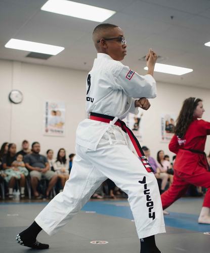 A boy in a white uniform strikes a front stance
