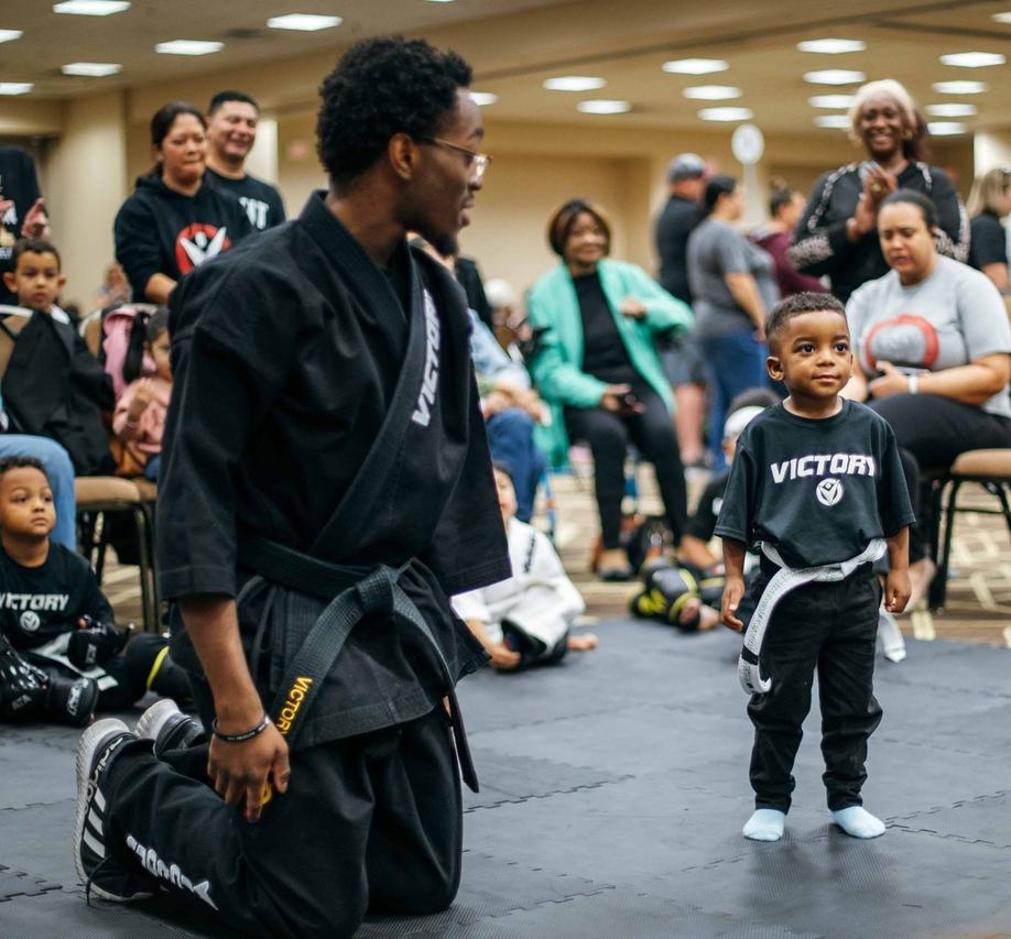 An instructor kneels to greet a young boy at eye level